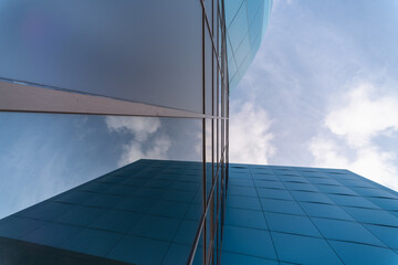 mirrored windows of the facade of an office building with blue panels and yellow window frames