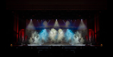 An empty stage of the theater, lit by spotlights and smoke before the performance