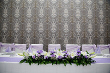 Closeup Of A Table Decorated With Purple Bows And Flower Bouquets For A Wedding Celebration