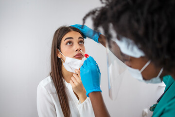 Doctor in protective workwear taking nose swab test from young woman. Close-up of woman having PCR testing at the hospital. Woman being screened for coronavirus in a laboratory