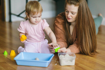 Wall Mural - A young mother and her one and a half year old daughter are sculpted from kinetic sand. Development of motor skills