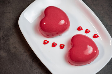 two pink mousse cakes on a white plate on a dark gray background