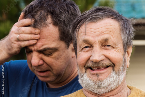 Laughing Elderly Man And A Distressed Adult Man
