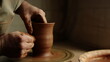 © stockbusters - Unknown clay artist sculpting in studio. Man hands forming jar in pottery