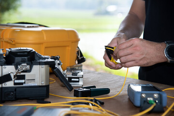 master's hands with optical fiber stripper