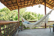 © EZ PHOTOS - Modern luxury summer holiday or vacation wooden beach house balcony with a hammock and rustic decoration with a green nature view.