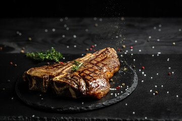 Canvas Print - Porterhouse beef steak cooked on a grill. Barbecue aged wagyu porterhouse steak. with spices on a black table, banner, catering menu recipe place for text