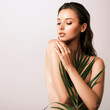 © Valua Vitaly - White woman with healthy skin of body and palm leaves. Tanned body of an attractive girl with green plants. Large palm leaves cover the body.