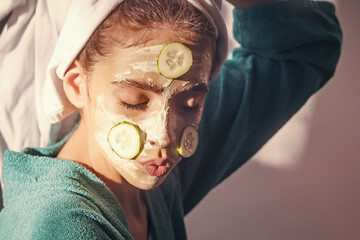 Girl or woman face with cucumber mask, towel on head. Skin and hair care, spa, wellness. Rejuvenation, health, youth.