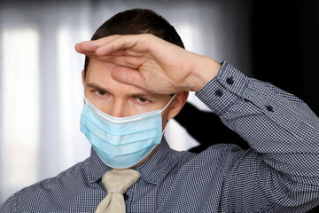 Coronavirus and fever symptoms, man in face mask and office clothes put his hand on forehead. Sick office worker, concept of headache, pressure or cold and flu