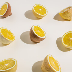 Pastel colored lemons cut in half on pastel background. Minimal summer, fruit or vegetarian concept. Flat lay.