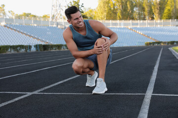 Canvas Print - Man in sportswear having knee problems at stadium