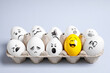 © New Africa - Yellow smiley egg among others with negative emotions in package on light background