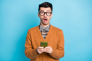 Sticker - Photo of nice impressed young guy dressed brown cardigan glasses texting modern device isolated blue color background