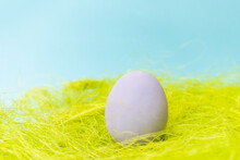 Purple Fancy Chicken Egg. Beautiful Easter Egg On Green Grass, Blue Background