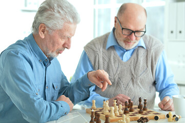 Poster - two senior couples sitting at table and playing chess