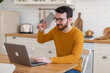 © Elena - Side view handsome young businessman in eyewear working with computer remotely, having chat with friends or collegs. Pleasant happy man communicating in social network