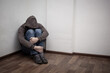 © dashtik - desperate young drug addict wearing hood and sitting alone in corner
