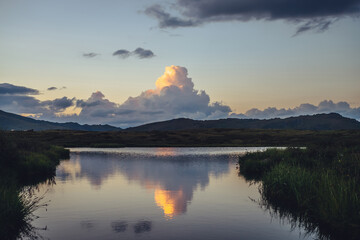 Wall Mural - scenic sunset landscape with yellow big cloud in form of explosion above mountain lake. awesome gian