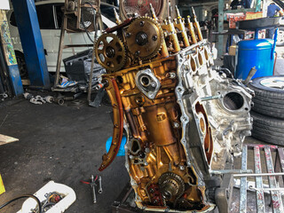 Wall Mural - Mechanic man dismantles the opposing car engine for repair at the stand in garage.