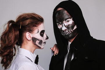 a girl and a man in Halloween makeup in the image of dead people with a black skull, wearing a black hoodie and a white shirt