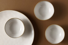 Empty Stoneware Plate And Bowls On Brown Table. Simple Decoration Flat Lay.