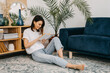 © Bostan Natalia - Happy young woman reading a book at home, sitting on the floor in living room.