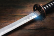 Katana sword on the brown wooden table background close up.