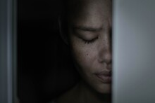 A Sad Afraid Woman Hiding In A Dark Closet Alone At Home.