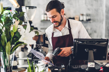 Portrait of handsome bearded barista man small business owner working with laptop computer behind the counter bar in a cafe