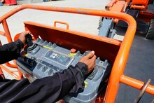 Workers Are Use Control Panel To Driving The Orange Articulate Boom Lift Or Telescopic Boom Lifts And Bucket Crane Mounted On Truck To Safety For Working At Heights And Articulating Boom Lift.
