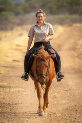 Sticker - Smiling blonde rides horse along dirt track