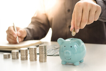 An Asian woman is putting coins into a piggy bank to practice saving discipline for future use, money saving concept.