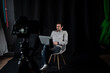 © Alexander - Man with laptop records video on camera in studio. Male vlogger in studio