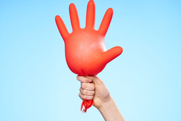 inflated rubber red glove in hand blue background and house cleaning