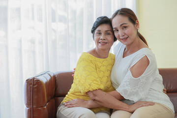 Asian middle-aged woman cuddles her older mother with love and care