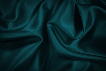 Black blue green abstract background. Dark green silk satin texture background. Beautiful wavy soft folds on the surface of the fabric. Teal elegant background with copy space for design. Web banner.