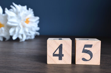 Wall Mural - Number 45, rating, award, Empty cover design in natural concept with a number cube and peony flower on wooden table for a background.