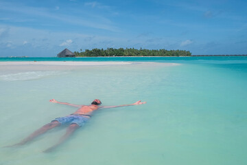 relaxed man floating in the sea on a paradisiacal island in the Maldives, Dhiffushi