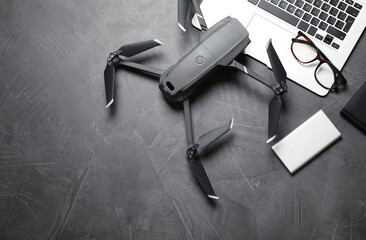 modern drone with video camera and laptop on grey stone table, flat lay. space for text