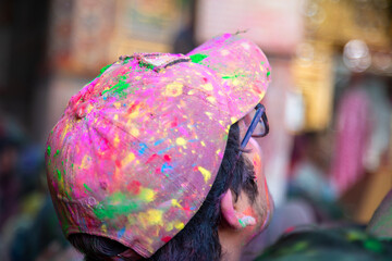 Young indian men celebrating holi festival, closeup of cap smeared with colored powder.