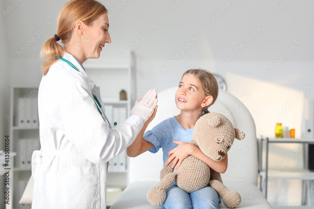 Pediatrician examining little girl in clinic