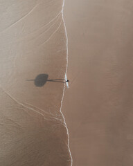 Shadow surfer walking along the shore