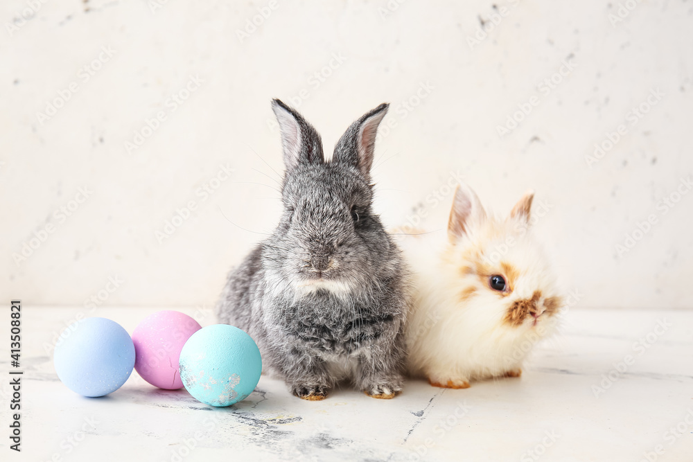 Cute rabbits and Easter eggs on light background