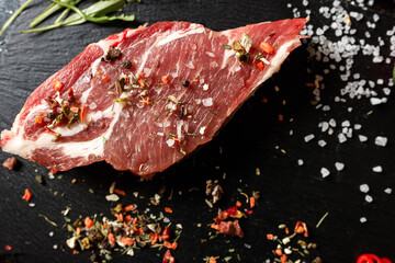 raw pork with spices for cooking on a fire or oven on a dark stone background