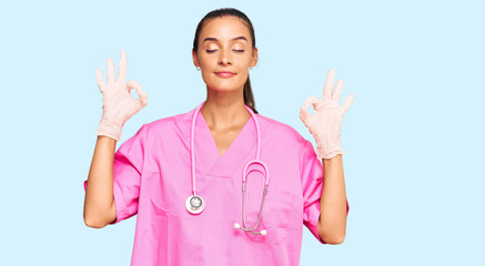 Wall Mural - Young hispanic woman wearing doctor uniform and stethoscope relax and smiling with eyes closed doing meditation gesture with fingers. yoga concept.