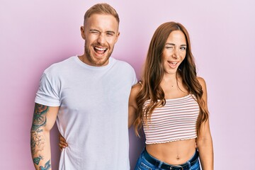 Young couple of girlfriend and boyfriend hugging and standing together winking looking at the camera with sexy expression, cheerful and happy face.