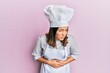 © Krakenimages.com - Young beautiful woman wearing professional cook uniform and hat with hand on stomach because nausea, painful disease feeling unwell. ache concept.