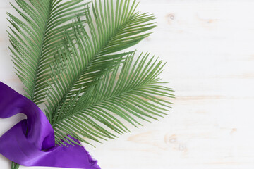 palms and purple sash on white wood background