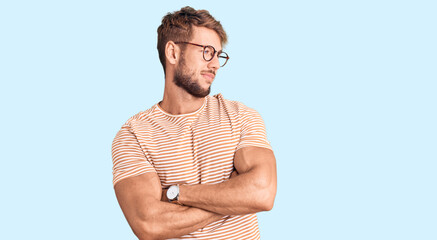 Young caucasian man wearing casual clothes and glasses looking to the side with arms crossed convinced and confident